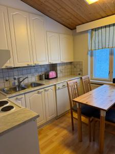 a kitchen with white cabinets and a wooden table at Guesthouse Sahanpera in Rovaniemi