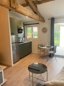 a kitchen and living room with a table and chairs at Logement neuf tout équipé avec terrasse, proche du bourg et des plages océanes, climatisé, WIFI, parking, linge et ménage compris, proche des commerces ouverts toute l'année in Mimizan