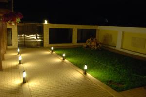 une terrasse avec des lumières sur l'herbe la nuit dans l'établissement Hotel Migador, à Eforie Sud