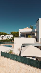 a white house with a white umbrella and a pool at Monte da Vinha By FHR in Quarteira
