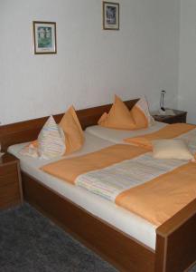 2 Betten mit orangefarbenen und weißen Kissen darauf in der Unterkunft Landhotel Sendes in Senden