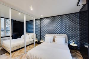 a bedroom with two beds and a blue wall at L'Appart Cosy- Hyper centre- Vue sur la collégiale in Brive-la-Gaillarde