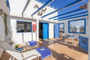 eine Terrasse mit Stühlen, einem Tisch und blauen Türen in der Unterkunft Ventanas De Lanzarote in Playa Quemada