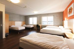 une chambre avec trois lits et des fenêtres dans l'établissement Sporthotel in der Sport Arena Siggenthal, à Villigen