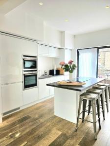a kitchen with white cabinets and a counter with stools at City Centre 3BR WiFi & Parking For Contractors & Families in Hull