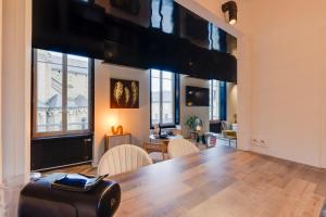 a room with a table and chairs and windows at L'Appart Cosy- Hyper centre- Vue sur la collégiale in Brive-la-Gaillarde