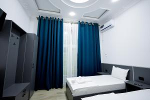Zimmer mit 2 Betten und einem Fenster mit blauen Vorhängen in der Unterkunft Chehran Hotel in Samarkand