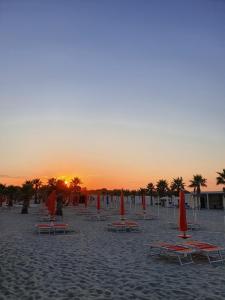 een groep stoelen en parasols op een strand bij zonsondergang bij Infinity Karla House 2 in Chioggia