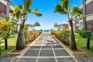 un chemin avec des palmiers devant les condos dans l'établissement Beachfront Le Cerisier Trou Aux Biches, Mon Choisy, à Mont Choisy 13 autres photos