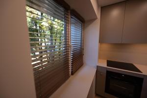 a kitchen with a large window with blinds on it at Vytauto 12 - jaukūs apartamentai centre - Self Check-in in Marijampolė +3 photos