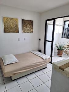 a bedroom with a bed in a room with white tiles at Polyglot Family in Natal