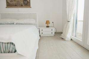 a white bedroom with a bed and a window at Irini in Mesochórion +2 photos