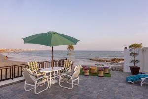 een tafel en stoelen met een parasol op het strand bij The Coastal Pearl in Karachi
