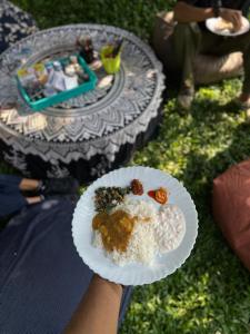 a person holding a plate of food with rice at Mango Trails - Farm Stay, Camping & Day Outing near Bangalore in Talai