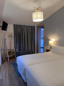 ein Schlafzimmer mit einem großen weißen Bett und einem Fenster in der Unterkunft HOTEL CASAS DA FORTALEZA Casa da Solaina in Outeiro de Rei