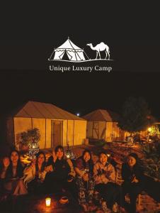 Un grupo de personas sentadas frente a un campamento de lujo con ukelele en Unique Luxury Camp, en Merzouga