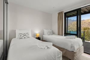two beds in a room with a window at Goldrush Way 4BR 3BA Lake & Mountain Views in Frankton Wharf