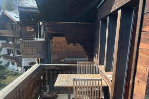 eine Veranda mit einem Holztisch und Stühlen auf einem Gebäude in der Unterkunft Dachferienwohnung Vieux Valais A, Ost-Mitte in Riederalp