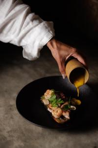 Una persona está vertiendo salsa en un plato de comida. en Txai Resort, en Itacaré