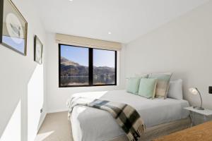 a white bedroom with a bed and a large window at Perfect on the Peninsula with Lake View and Hot Tub in Frankton Wharf