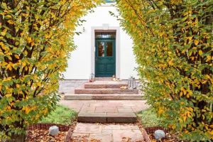 une porte verte dans une maison blanche entourée d'arbres dans l'établissement Saar-Lor-Lux-Perle, à Merzig
