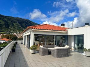 a balcony of a house with wicker furniture on it at Beachfront Penthouse with Panoramic Ocean-View Terrace VIP Baia in Machico