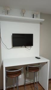 una scrivania con 2 sgabelli e una TV a muro di Suite Praia da Costa Confort a Vila Velha