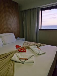 una stanza d'albergo con un letto con asciugamani sopra di Suite Praia da Costa Confort a Vila Velha Altre 29 foto