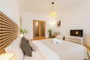 a bedroom with a large white bed and a tv at Budovatelska Apartment in Bratislava