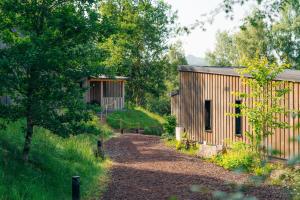 a wooden building next to a dirt road at Hôtel - Lodges de Lemptégy in Saint-Ours