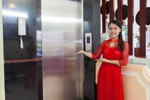 una donna con un vestito rosso davanti a un frigorifero di Ninh Binh Family Hotel a Ninh Binh