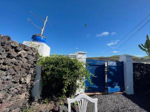 Ein weißer Stuhl befindet sich vor einem Haus mit blauer Tür in der Unterkunft Schön eingerichtetes Bauernhaus mit privaten Gärten in hübschen Dorf nur wenige Kilometer zum Meer in Uga