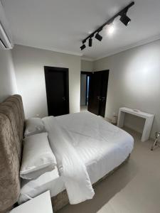 Un dormitorio con una cama blanca grande y una mesa en شقة متكاملة بجوار ملعب الجوهرة, en Yeda 13 fotos más