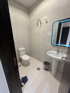 une salle de bain avec toilettes, lavabo et miroir dans l'établissement شقة متكاملة بجوار ملعب الجوهرة, à Djeddah