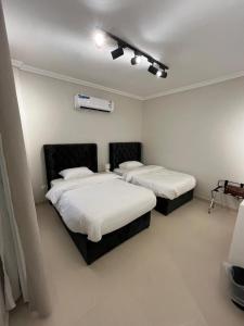 une chambre avec deux lits avec des draps blancs dans l'établissement شقة متكاملة بجوار ملعب الجوهرة, à Djeddah