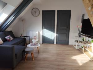 a living room with a couch and a clock on the wall at Très joli F4 neuf au pied du Château avec jardin in Rouffach
