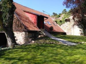 a house with a red roof and a grass yard at Très joli F4 neuf au pied du Château avec jardin in Rouffach