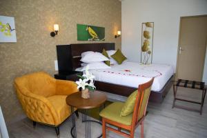 a hotel room with a bed and a chair and a table at Hôtel du parc exotique in Mbour
