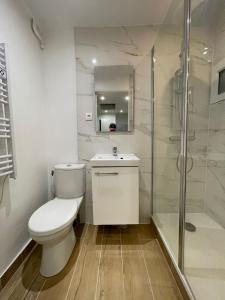 a white bathroom with a toilet and a shower at Grande maison rénovée, 10 pers, métro 7 min, Paris centre 20 min, supermarché 100 m in Romainville