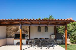 a patio with a table and chairs under a pergola at Ferienvilla Malvasia Mit Swimmingpool Auf Kreta in Roúpai
