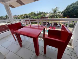 a red table and chairs on a balcony at Jade in Assinie