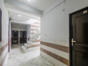 um corredor com escadas e uma porta preta em Hotel O Red Rose em Nova Deli