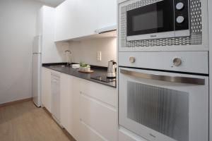 eine weiße Küche mit einer Mikrowelle über einem Backofen in der Unterkunft ITURRIONDO by Urdaibai Experience in Gernika + 7 Fotos