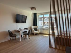 ein Wohnzimmer mit Tisch und Stühlen und einem Fenster in der Unterkunft SkyWay by NightSpace- Modern City Apartment in Sofia