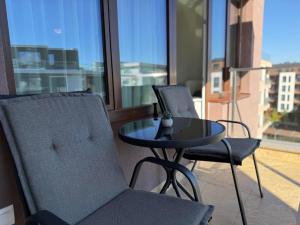 2 Stühle und ein Glastisch auf dem Balkon in der Unterkunft SkyWay by NightSpace- Modern City Apartment in Sofia
