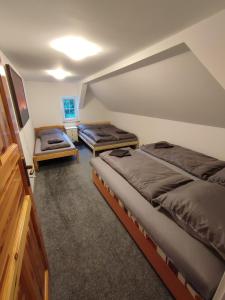 a attic bedroom with two beds and a tv at Chata Luisa in Nová Komora