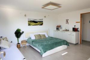 ein weißes Schlafzimmer mit Bett und Küche in der Unterkunft Suite Golan in Neot Golan