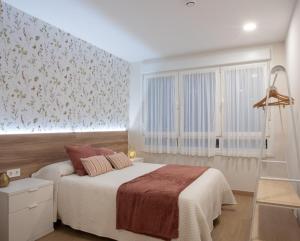 une chambre avec un lit et un mur fleuri dans l'établissement ITURRIONDO by Urdaibai Experience, à Guernica y Luno