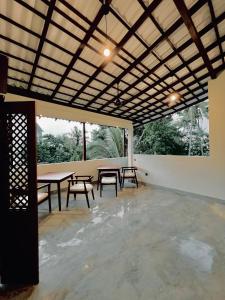 Calm Aruna Boutique Lodge - Mirissa في ميريسا: غرفة بها طاولات وكراسي ونافذة كبيرة