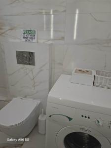 ein weißes Bad mit einer Waschmaschine und einem WC in der Unterkunft Lagonissi Summer House in Lagonisi